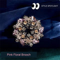 Pink floral brooch with faceted decorative accents on dark blue fabric