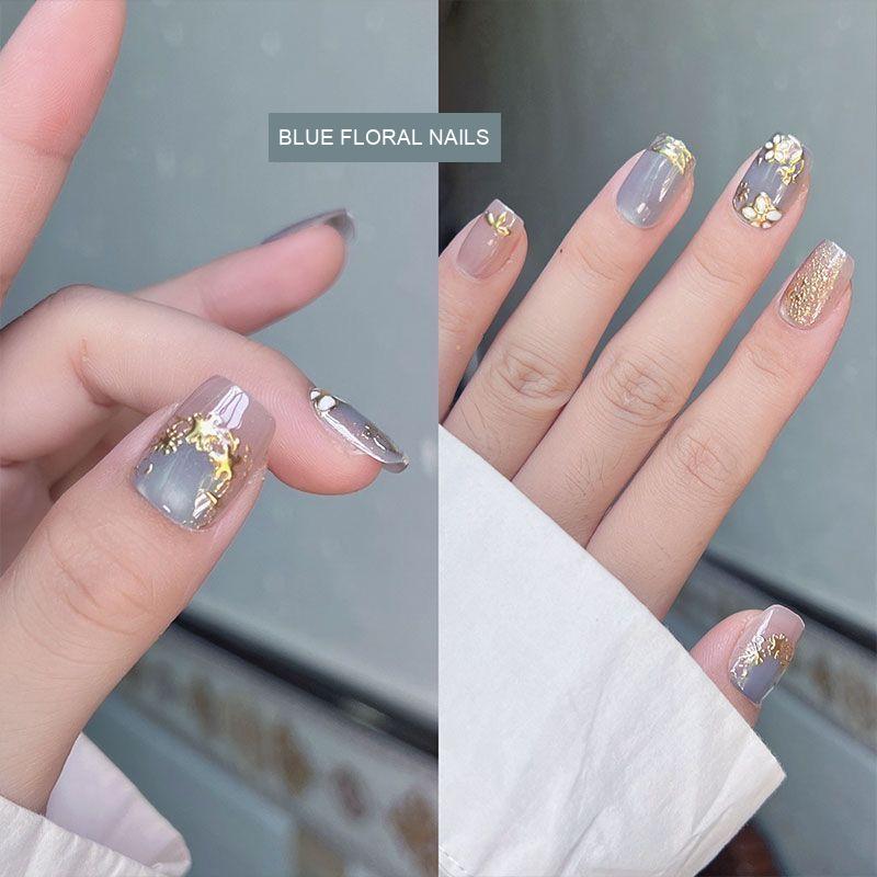 Blue floral cat-eye press-on nails shown worn, with floral and glitter accent nails